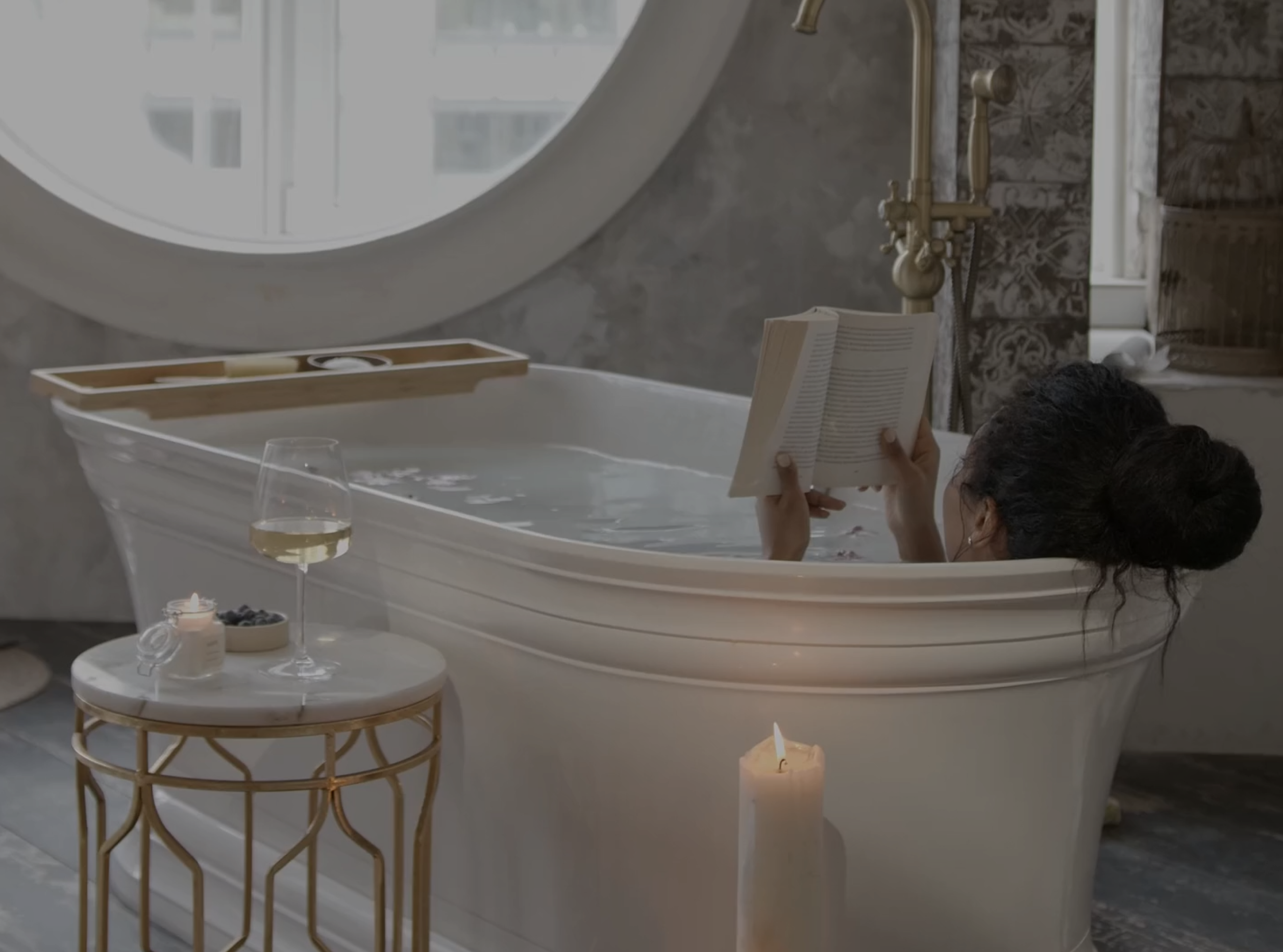 A woman relaxing with a book in a luxurious, deep-soaking bathtub that has a perfect, high-gloss finish from an Armoglaze restoration.
